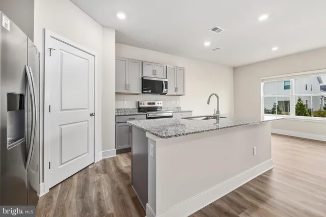 a kitchen with granite countertop a refrigerator stove top oven and sink