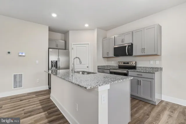 a kitchen with stainless steel appliances granite countertop a stove a sink and a refrigerator