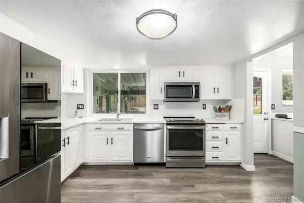 a kitchen with stainless steel appliances white cabinets a stove a sink and a microwave