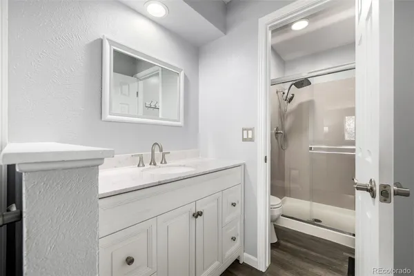 a bathroom with a granite countertop sink toilet and shower