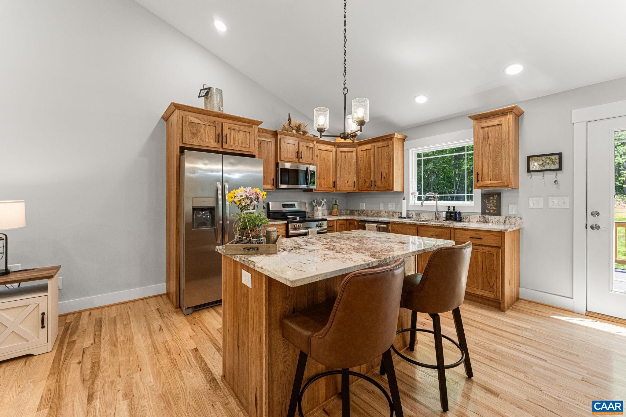 230 Fox Hollow Road Ruckersville, VA 22968 - Photo 15 of 42 a kitchen with stainless steel appliances granite countertop a kitchen island a stove a refrigerator a sink a dining table and chairs with wooden floor