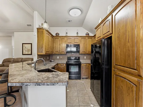a kitchen with granite countertop stainless steel appliances a stove refrigerator and cabinets
