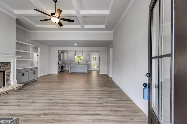 a view of an empty room with a window and wooden floor