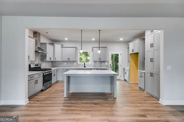 a large kitchen with stainless steel appliances kitchen island granite countertop a stove and a refrigerator
