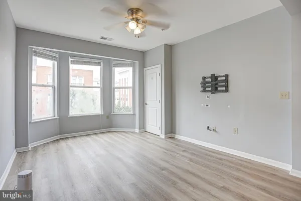 an empty room with wooden floor and windows