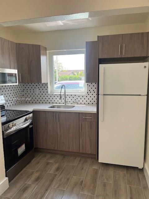 1151 West 28th Street, Unit 1 Hialeah, FL 33010 - Photo 7 of 25 a kitchen with granite countertop a sink a stove a refrigerator a washer and dryer with wooden floor