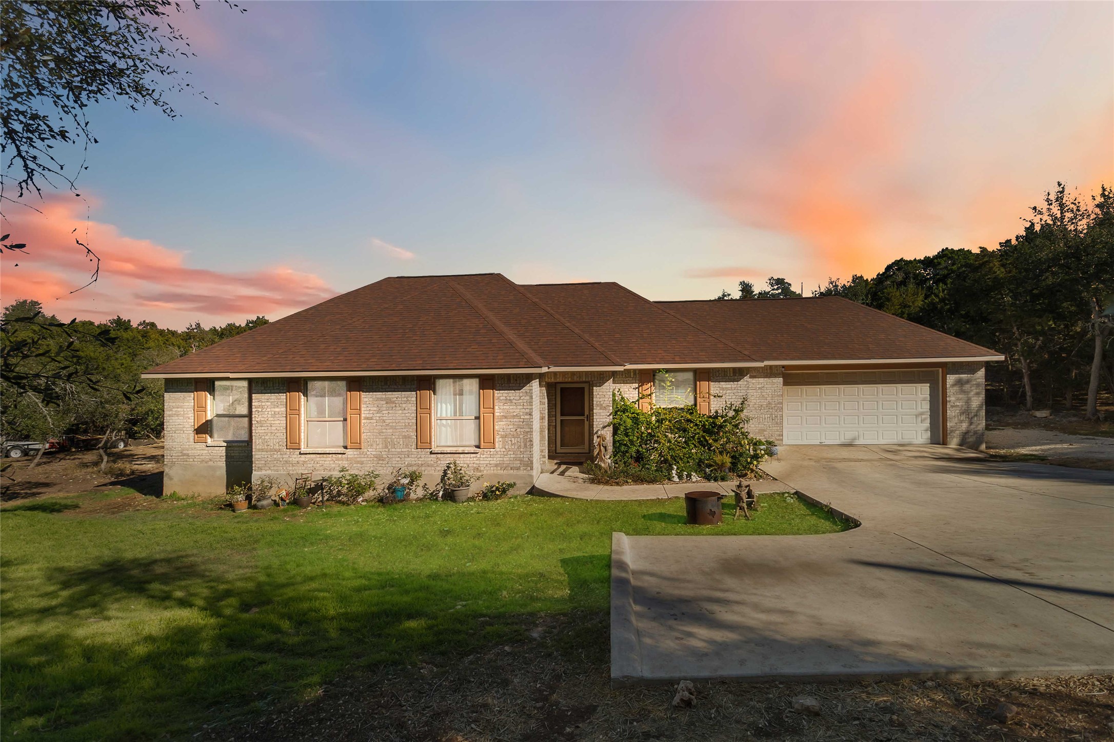 Single story home featuring a yard, driveway, brick exterior and a two car garage
