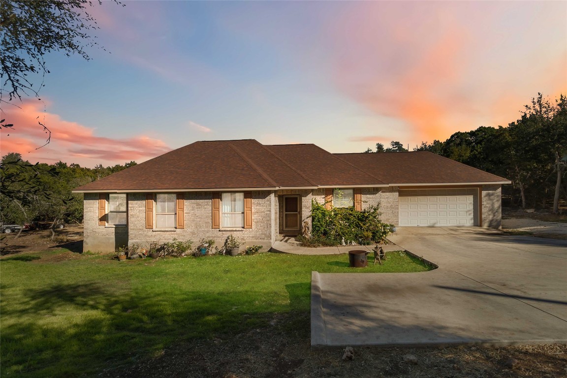Single story home featuring a yard, driveway, brick exterior and a two car garage