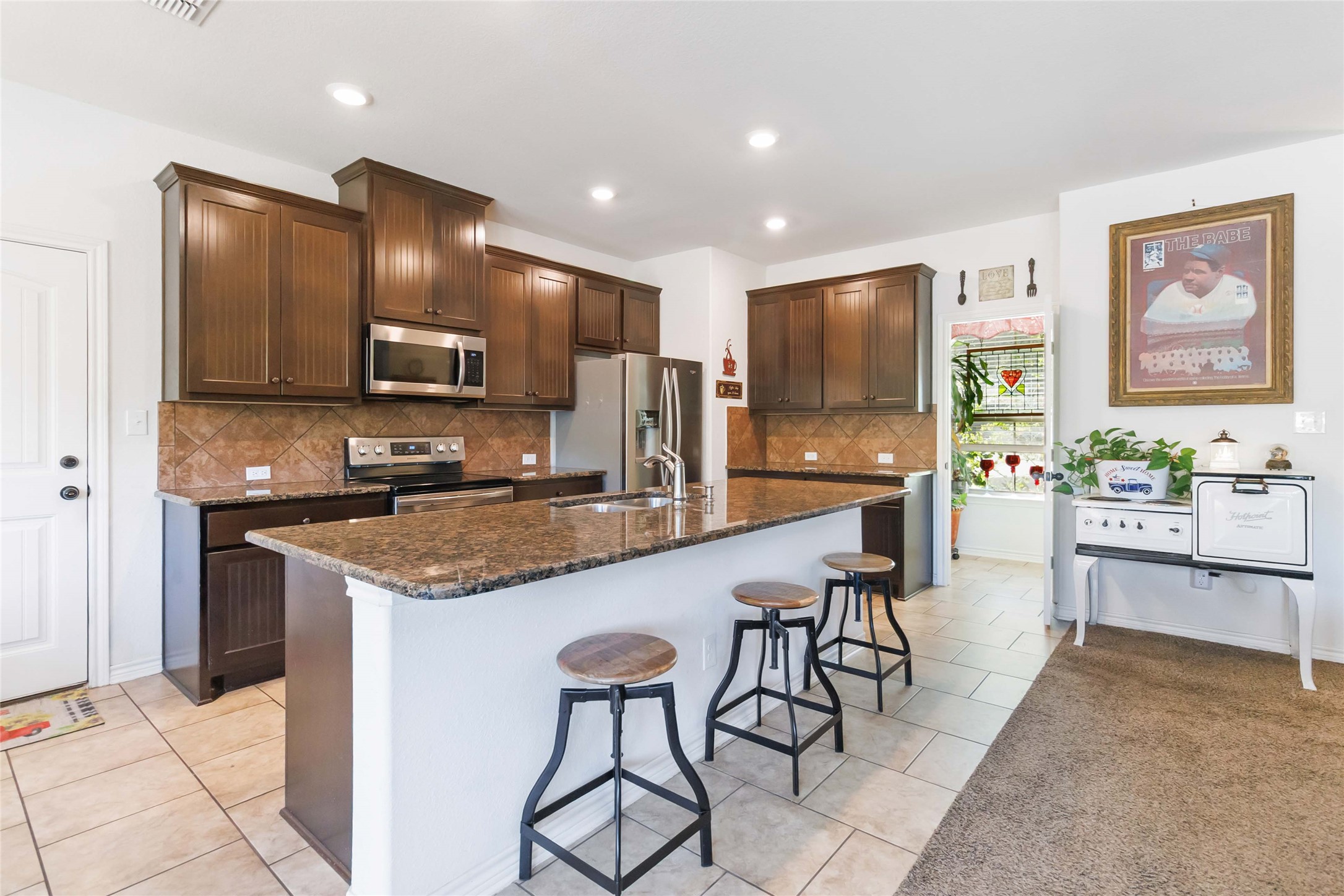 1193 Persimmon Pass Fischer, TX 78623 - Photo 8 of 27 a kitchen with stainless steel appliances granite countertop a stove top oven a sink a refrigerator and chairs