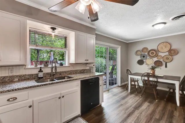 a kitchen with stainless steel appliances granite countertop a stove a sink a dining table and chairs with wooden floor