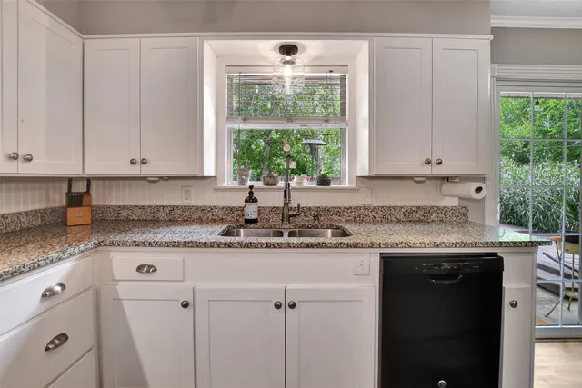 a kitchen with granite countertop white cabinets and a window