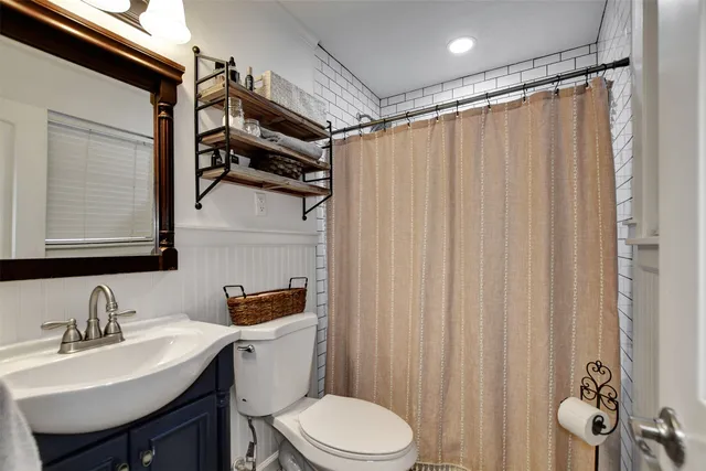a bathroom with a sink a toilet and shower curtain