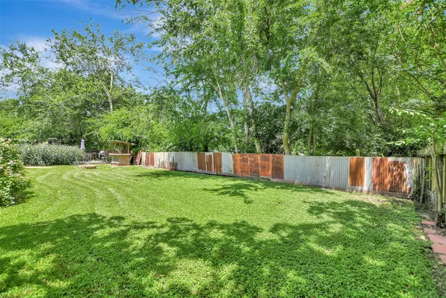 a view of a backyard with a fence and trees