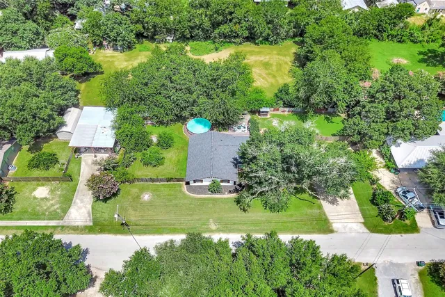 an aerial view of residential house with outdoor space and trees all around