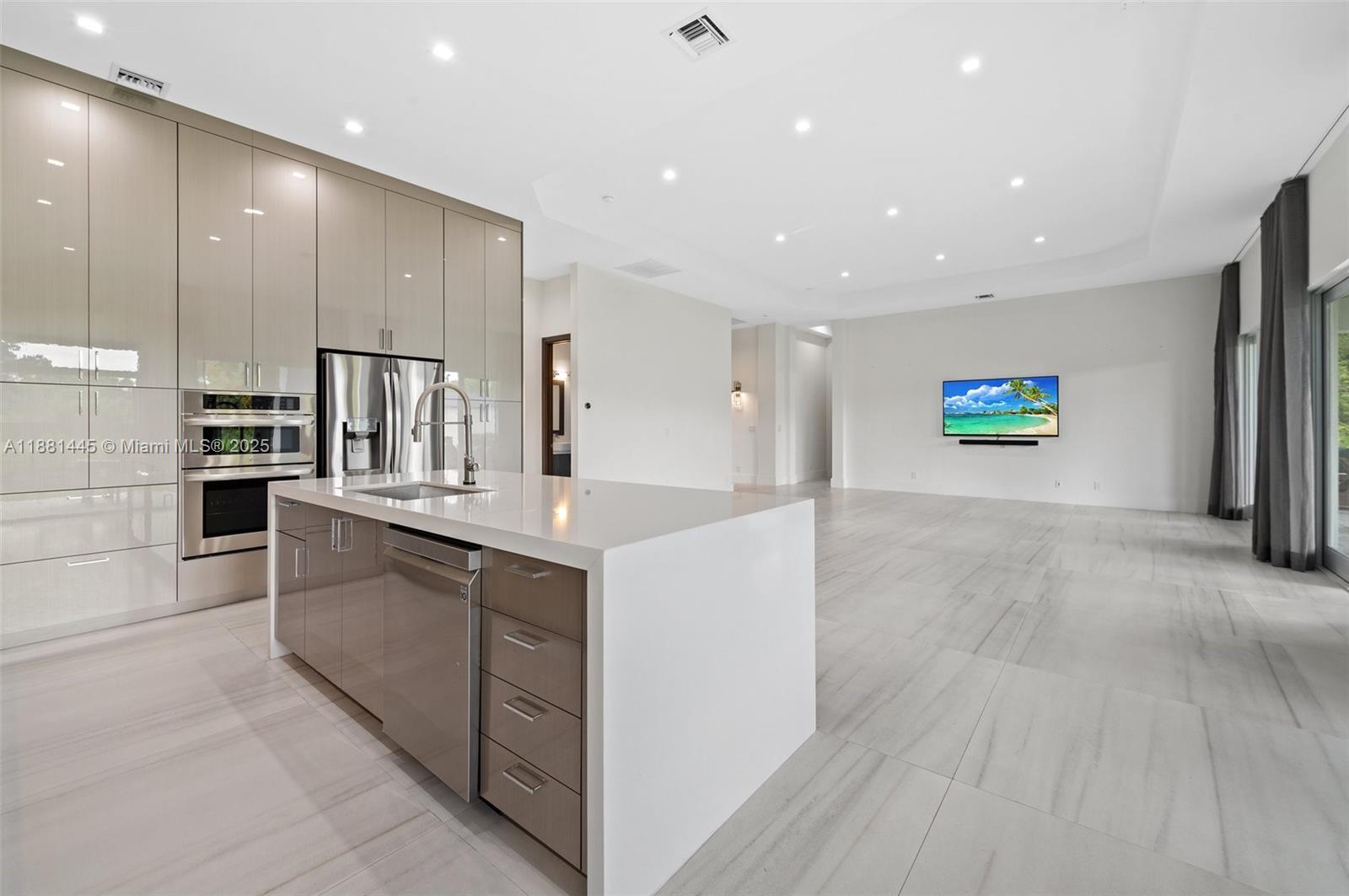 2400 Southwest 112th Avenue Davie, FL 33325 - Photo 22 of 61 a large white kitchen with kitchen island a sink a stove a refrigerator and white cabinets