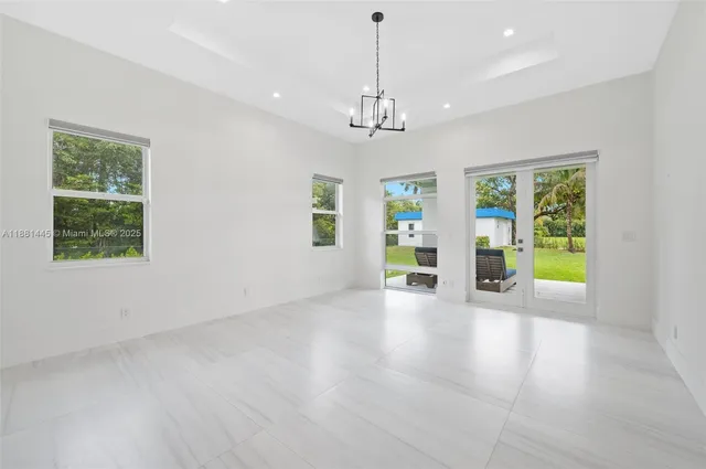 a view of an empty room with chandelier fan and window