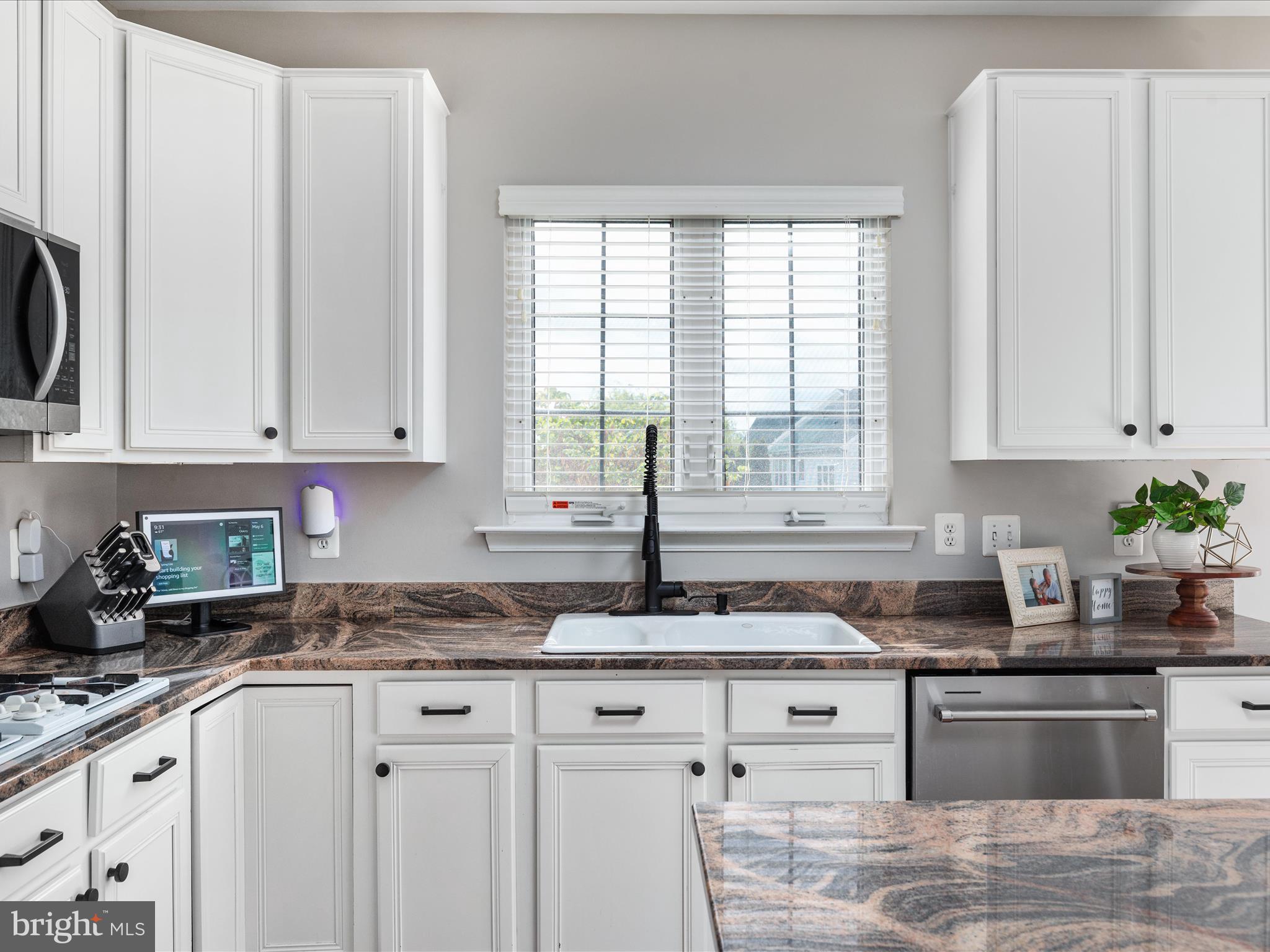 8705 Lords View Loop Gainesville, VA 20155 - Photo 10 of 58 a kitchen with granite countertop white cabinets stainless steel appliances a sink and a window
