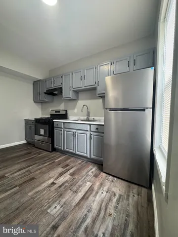 a kitchen with a refrigerator a stove top oven and cabinets