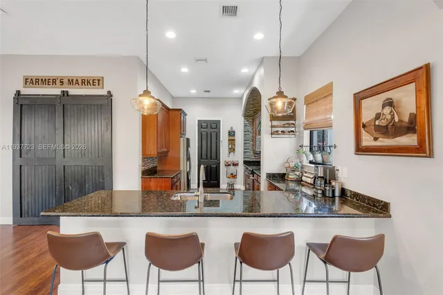 a kitchen with granite countertop a dining table chairs and white cabinets