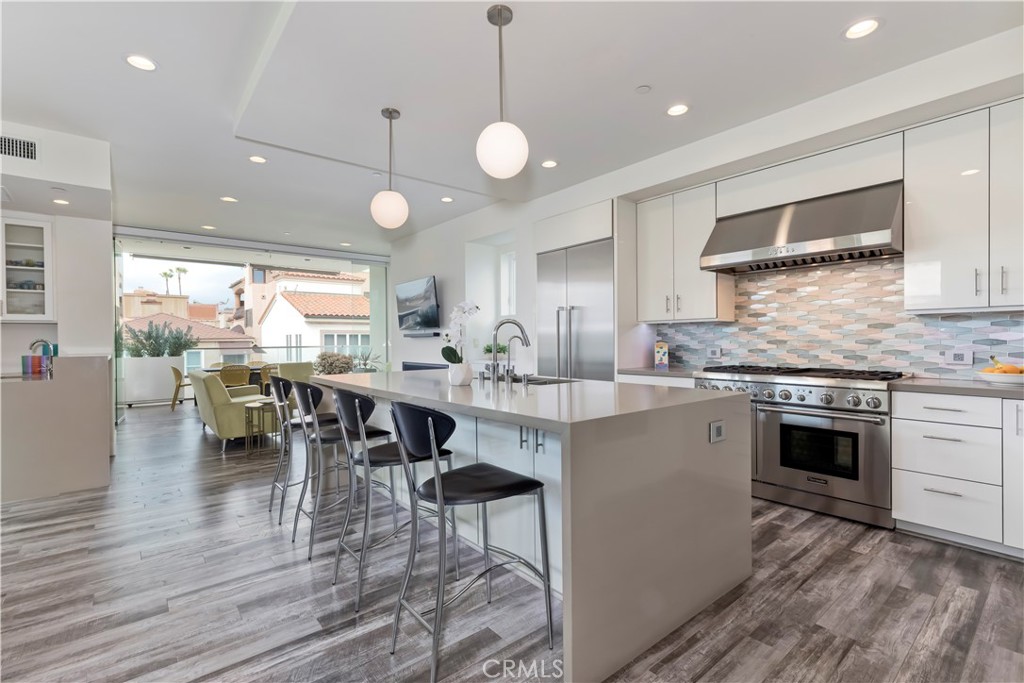 48 57th Place Long Beach, CA 90803 - Photo 15 of 47 a kitchen with stainless steel appliances kitchen island granite countertop a stove a sink a dining table and chairs with wooden floor