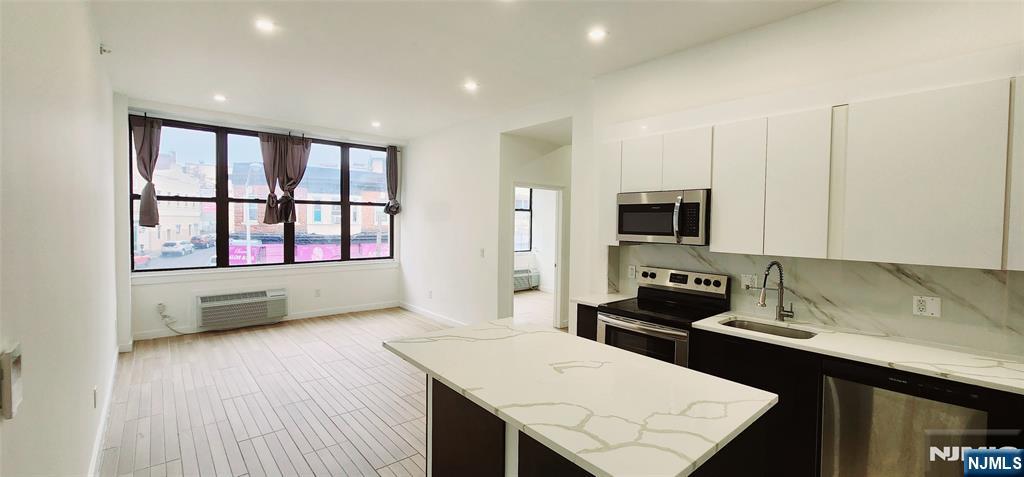 30 Howe Avenue, Unit 201 Passaic, NJ 07055 - Photo 3 of 6 a kitchen with stainless steel appliances kitchen island granite countertop a stove a sink and a microwave