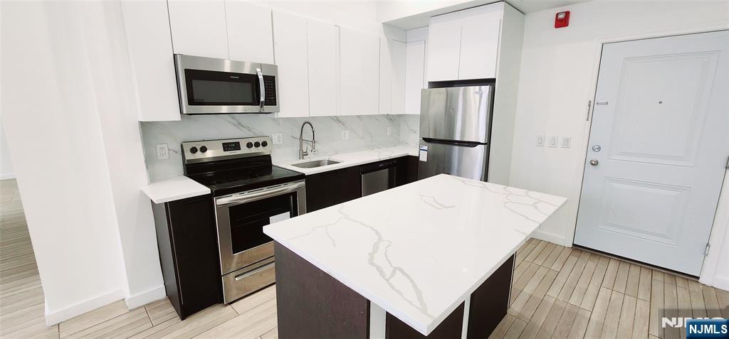 30 Howe Avenue, Unit 201 Passaic, NJ 07055 - Photo 5 of 6 a kitchen with a refrigerator stove and microwave