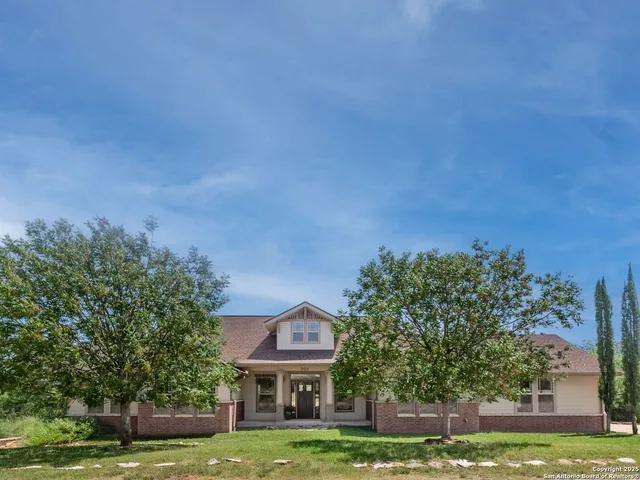 a front view of a house with a garden and trees