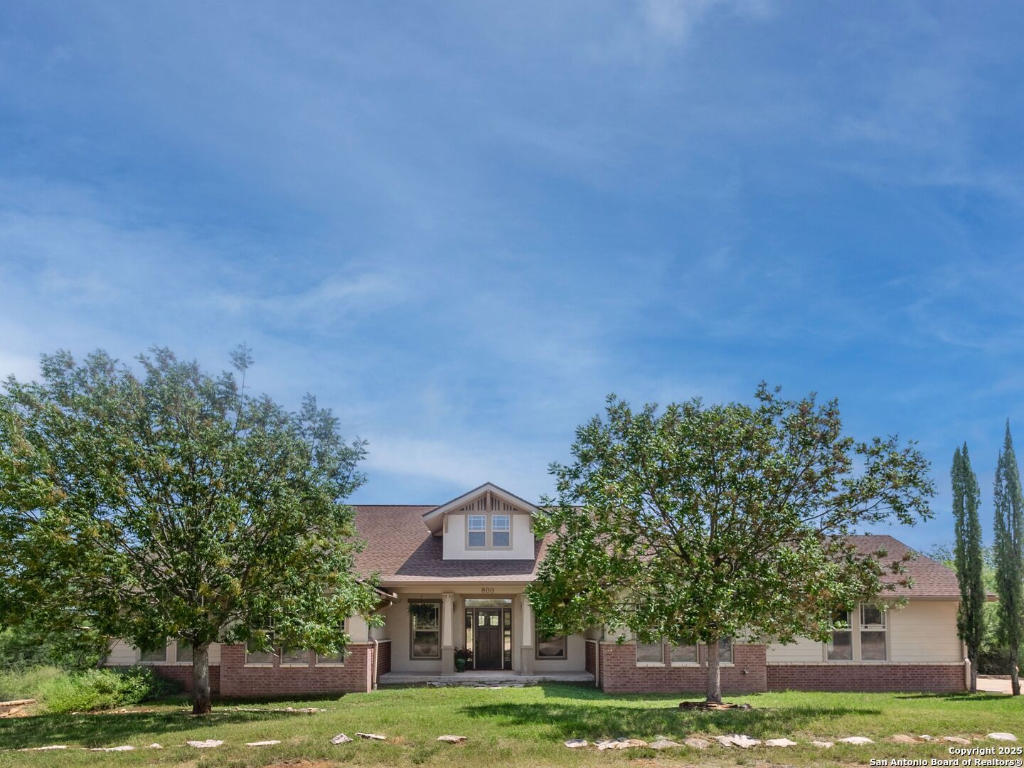 a front view of a house with a garden and trees