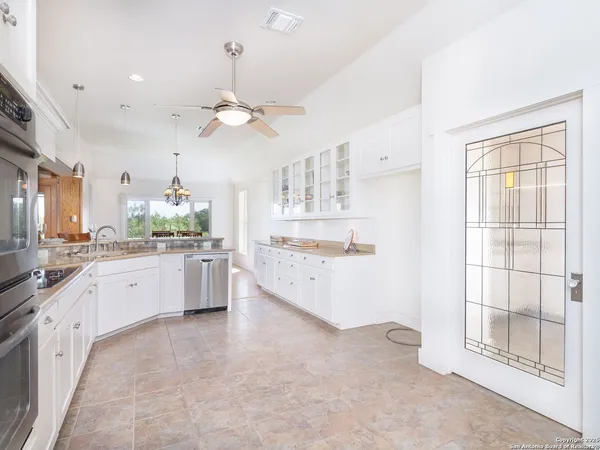 a large white kitchen with a large window a sink and stainless steel appliances