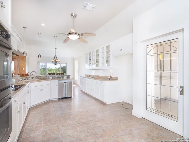 a large white kitchen with a large window a sink and stainless steel appliances