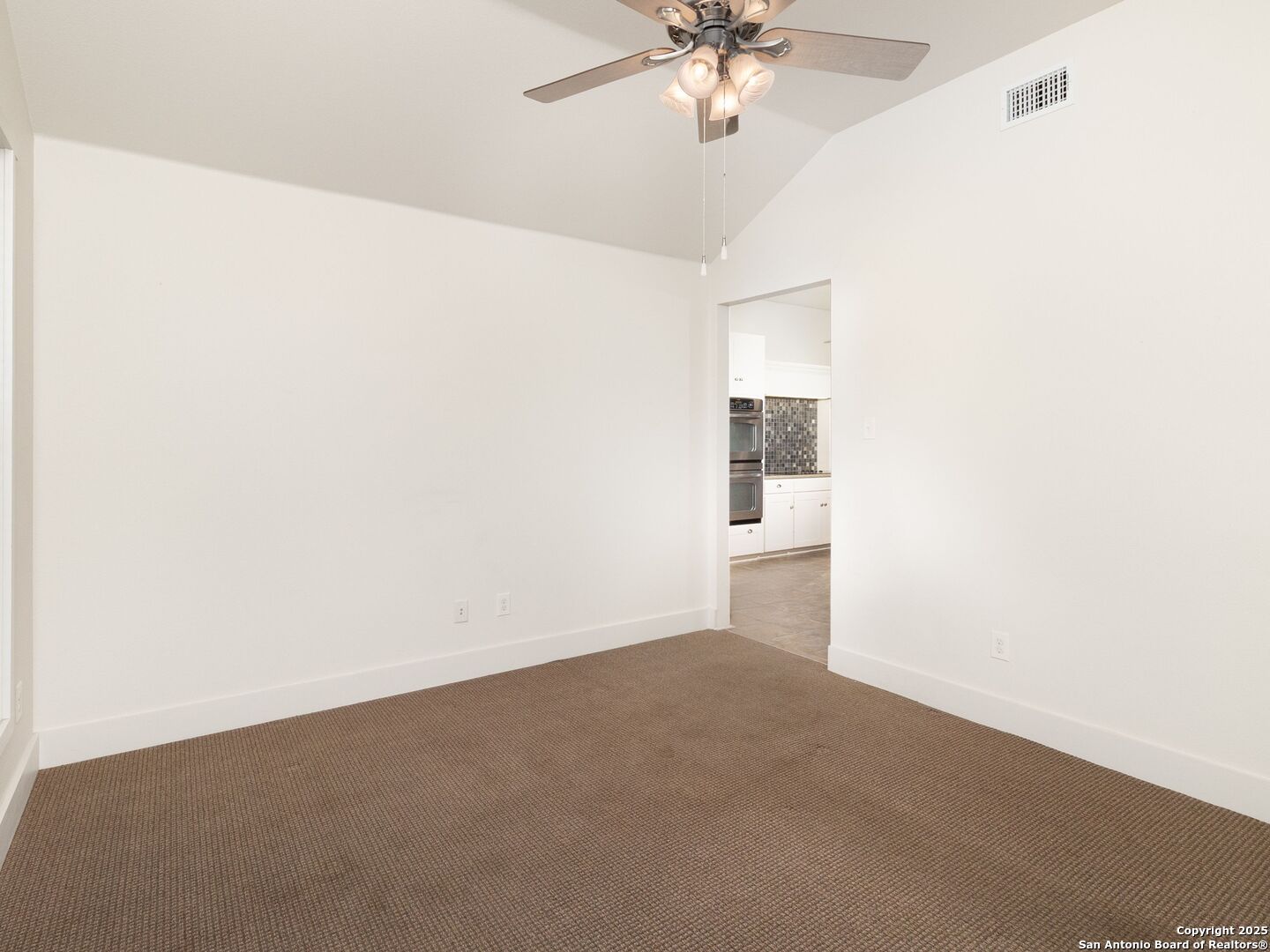 800 Steapp Lane Mason, TX 76856 - Photo 30 of 47 an empty room with a chandelier fan and kitchen view