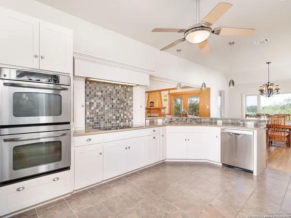 a kitchen with granite countertop white cabinets stainless steel appliances and a counter space
