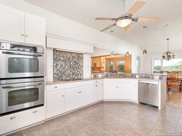a kitchen with granite countertop white cabinets stainless steel appliances and a counter space