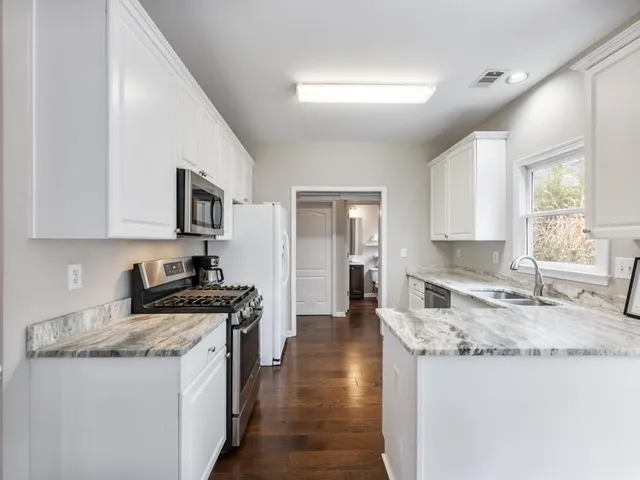 a bedroom with a large bed couch and two windows