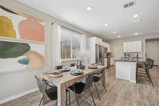 a kitchen with a dining table chairs and refrigerator