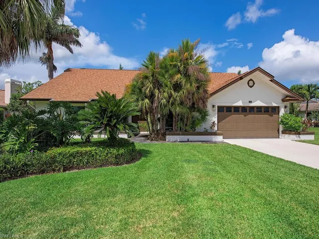 a front view of a house with a yard and palm tree