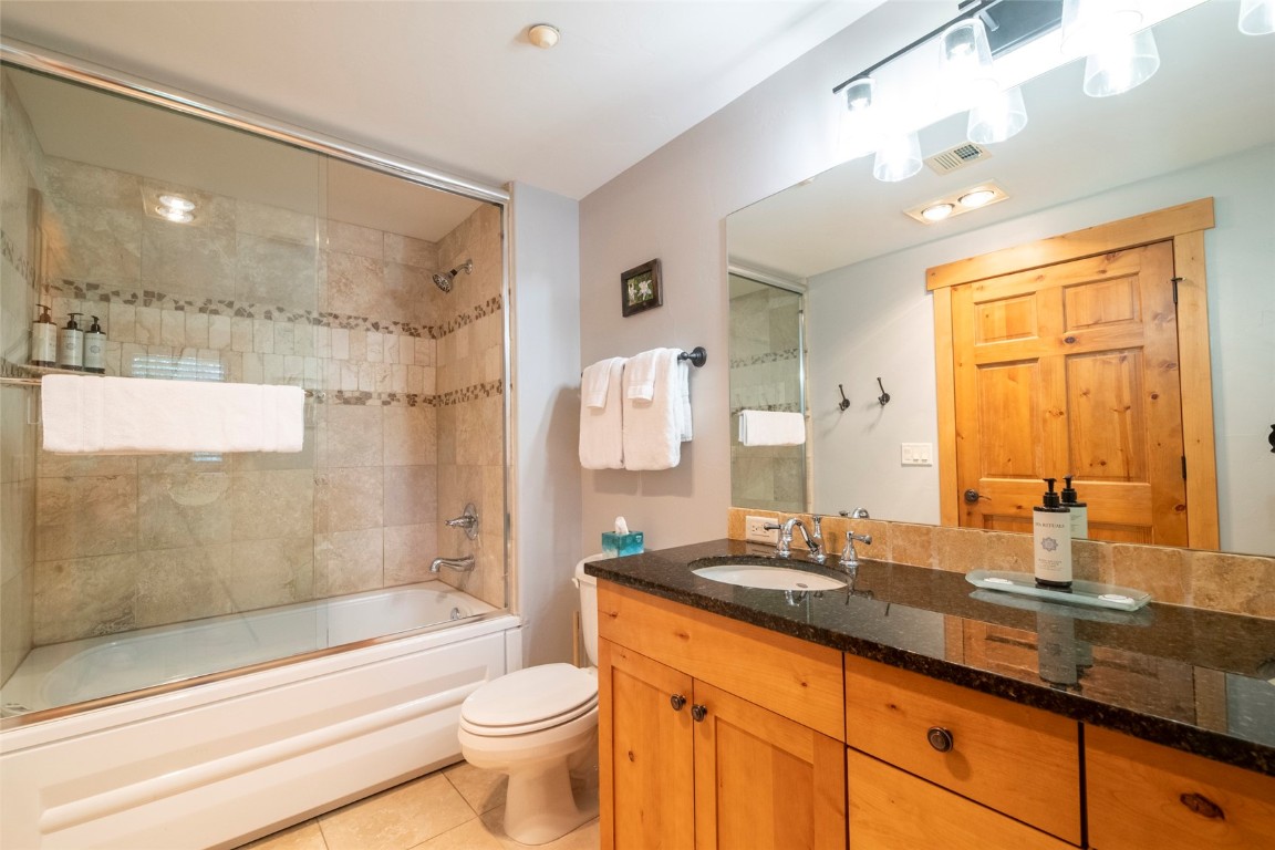 1875 Medicine Springs Road, Unit 4205 Steamboat Springs, CO 80487 - Photo 17 of 43 a bathroom with a granite countertop sink a toilet a mirror and shower