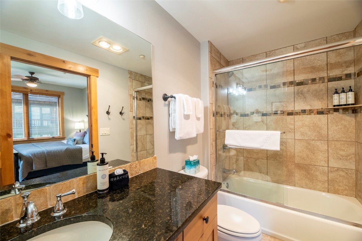 1875 Medicine Springs Road, Unit 4205 Steamboat Springs, CO 80487 - Photo 26 of 43 a bathroom with a granite countertop sink mirror toilet and bathtub