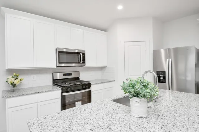 a kitchen with stainless steel appliances kitchen island granite countertop a refrigerator stove and sink