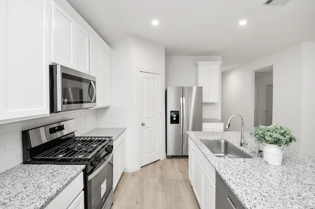 a kitchen with stainless steel appliances granite countertop a sink stove and refrigerator