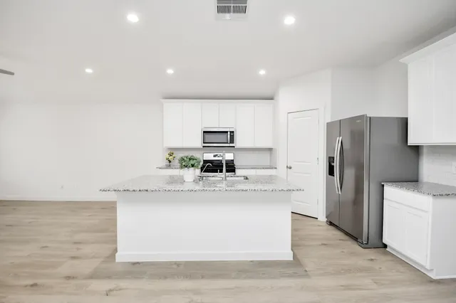 a large kitchen with stainless steel appliances granite countertop a stove a sink and a refrigerator