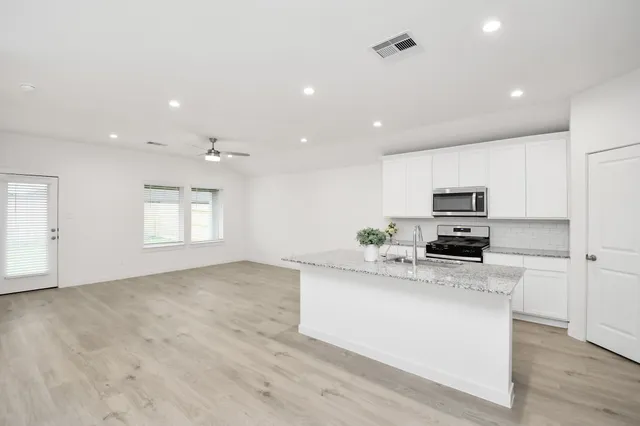 a kitchen with stainless steel appliances a microwave a sink a stove a microwave and a refrigerator