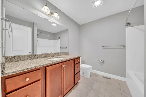 a bathroom with a granite countertop sink a toilet and shower