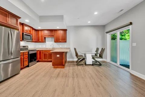 a kitchen with stainless steel appliances granite countertop a refrigerator a sink a stove and a wooden floors