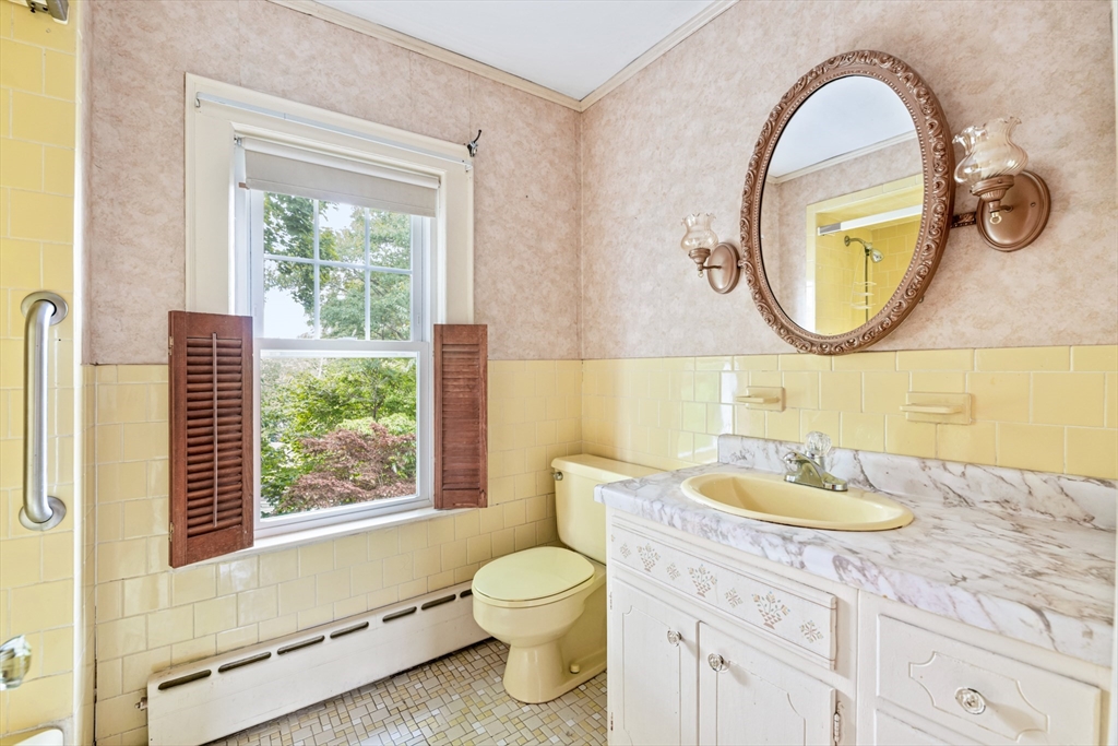 277 Appleton Street Arlington, MA 02476 - Photo 15 of 21 a bathroom with a granite countertop toilet a sink a mirror and a window