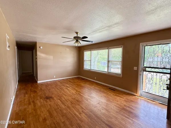 a view of an empty room with a window and wooden floor