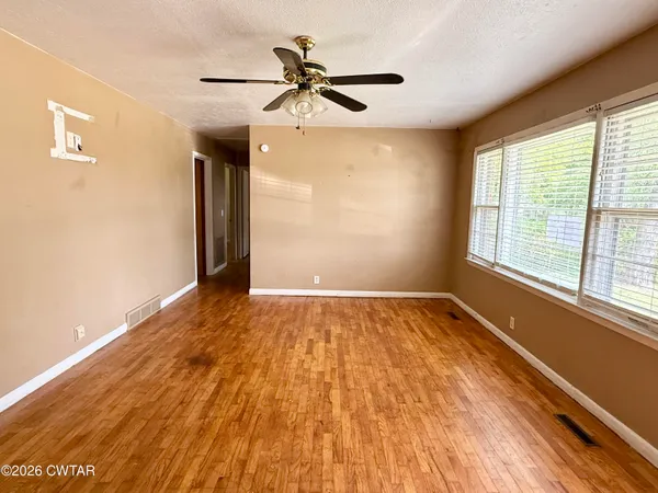 a view of empty room with wooden floor and fan