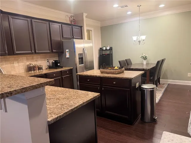 a kitchen with stainless steel appliances kitchen island granite countertop a sink stove and refrigerator
