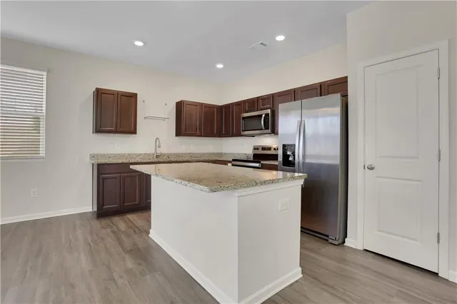 a kitchen with kitchen island a counter top a sink stainless steel appliances and cabinets