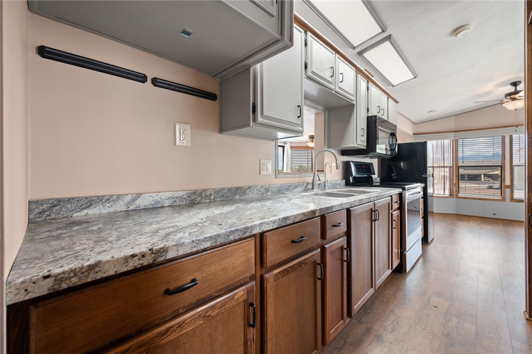 2000 Ramar Road, Unit 587 Bullhead City, AZ 86442 - Photo 25 of 79 Kitchen with stainless steel electric stove, lofted ceiling, light wood finished floors, ceiling fan, and black microwave